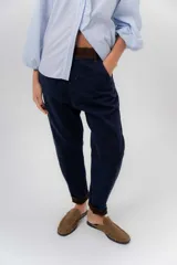 Pantalón de gabardina azul marino, de corte barrel y tiro bajo, con detalles en pana marrón en la pretina y en el ruedo interior vuelto.