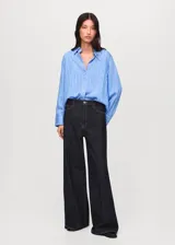 Camisa de corte recto y diseño a rayas verticales, con cuello camisero, cierre frontal de botones y mangas largas con puños abotonados.