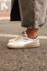 Zapatillas plateadas de cuero vacuno con cordones color beige y suela color caramelo.