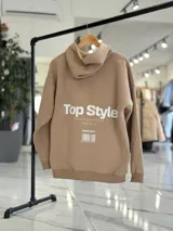 Canguro negro oversize con capucha y gran estampado blanco en la espalda con el texto "Top Style", "Dream big. Work hard. Make it real.", "SINCE 2021" y un código de barras.