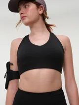 Top deportivo negro con espalda nadadora, copas removibles y detalle de logo sutil en el elástico inferior.