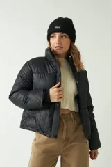 Campera puffer negra con cuello alto y cierre frontal con botones a presión.