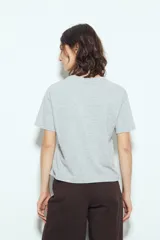 Remera blanca de manga corta con estampa frontal de un personaje con lentes de sol y la frase "Llegué tarde porque no quería venir". Tiene silueta relajada y calce cómodo, con un corte asimétrico en el bajo.