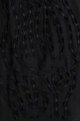 Blusa oversized color negro en tejido liviano de mezcla de lino y viscosa, con cuello elevado plisado y abertura en V con tiras finas. Mangas raglán extralargas con detalles bordados tono sobre tono y puños acampanados con pliegues.