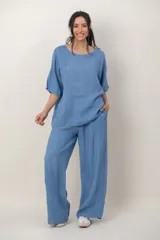 Blusa de lino color azul, de corte holgado, con cuello redondo, mangas cortas y detalle de alforzas verticales en un lateral.