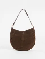 Cartera de hombro tipo hobo color verde claro, confeccionada en gamuza sintética. Presenta detalles de ojales metálicos plateados en los laterales y la base, entrelazados con tiras del mismo material, y una única asa corta para el hombro sujeta por argollas metálicas.