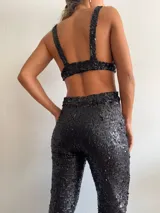Pantalón de lentejuelas negro con aberturas en la cadera y corte recto.