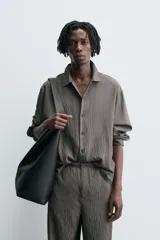 Camisa de corte relajado confeccionada en tejido fluido con mezcla de modal, presenta un diseño de rayas verticales con textura efecto arrugado, cuello solapa, cierre frontal de botones y manga larga con puños abotonados.