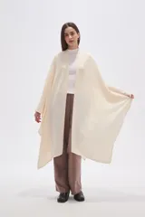 Poncho abierto color crudo, de diseño holgado y caída fluida.