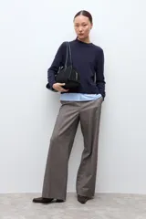 Sweater azul marino de manga larga con cuello redondo, combinado con una camisa celeste que se asoma por debajo.