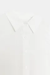 Camisa blanca de manga larga con corte amplio y puños anchos. Presenta cuello solapa y cierre frontal con botones.