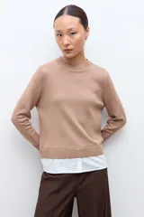 Sweater azul marino de manga larga con cuello redondo, combinado con una camisa celeste que se asoma por debajo.