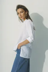 Camisa blanca de lino con cuello clásico, manga larga con puños abotonados y cierre frontal con botones. Corte recto y holgado.