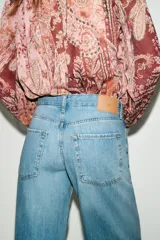 Jeans de tiro bajo color azul claro, con cinco bolsillos y pernera ancha. Cierre frontal con cremallera y botón.