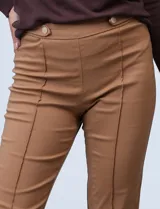 Pantalón negro de gabardina elastizada, corte slim, con pretina ancha con aplique de botones y largo de pierna pespunteado.