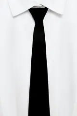Camisa de algodón de corte recto con cuello solapa, manga corta y cierre frontal con botones ocultos. Presenta un diseño con pechera y una corbata negra extraíble a contraste.