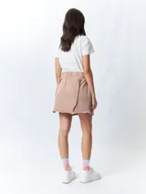 Minifalda color beige con elástico en la cintura, cordones ajustables y costuras marcadas en los laterales.