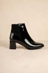 Botas de caña baja color negro charol, con punta fina, cierre lateral y taco cuadrado.