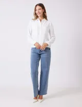 Camisa de crepe color beige con cuello clásico, cierre frontal con botones y dos bolsillos aplicados en el pecho.