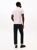 Chomba Tommy Hilfiger color rosado de corte regular, confeccionada en tejido jacquard de mezcla de algodón BCI y poliéster reciclado. Cuenta con cuello tipo chomba, billetera de dos botones, detalles distintivos de la marca y logo bordado en la manga.