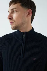 Sweater gris de punto con cuello alto y medio cierre con cremallera.
