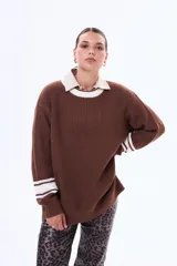 Sweater de punto color marrón con cuello redondo, puños y cuello con detalles de rayas blancas en contraste. De corte holgado y manga larga.
