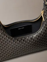 Cartera de hombro de Calvin Klein en color negro con estampado integral geométrico y de monograma. Cuenta con cierre de cremallera superior y una correa ajustable.