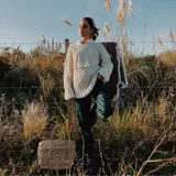Sweater de lana merino color marfil, tejido a mano con puntos combinados de trenzas, bodoques y punto panal, de mangas largas y silueta relajada.