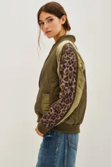 Campera tipo bomber acolchada en color verde militar, con mangas largas que presentan paneles laterales con estampado animal print. Cuenta con cierre frontal, cuello, puños y ruedo en tejido rib elástico.