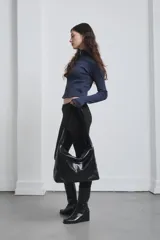 Bolso tipo hobo de cuero negro con correa ancha para el hombro.