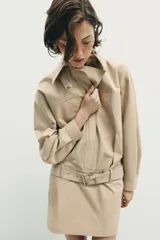 Vestido corto de cuello solapa y manga larga, con bolsillos delanteros y detalle de cinturón a tono. Presenta cierre frontal con cremallera oculta y bajo con aberturas laterales.