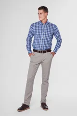 Pantalón de gabardina color marrón claro, corte slim fit, con bolsillos laterales y traseros. Se ajusta a la cintura con cinturón de cuero marrón.