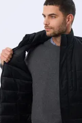 Chaleco reversible capitoneado de corte estándar, con cuello alto, cierre frontal de cremallera y botones a presión. Cuenta con bolsillos laterales y un bolsillo vertical en el pecho.