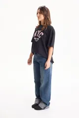 Remera de algodón negra de manga corta y corte holgado, con estampa frontal con la inscripción "NYC New York The Big Apple City".