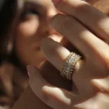 Anillo dorado con tres hileras de cristales blancos de diferentes tamaños.
