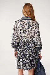 Vestido camisero corto de Ba&sh con estampado floral en tonos azul marino y blanco. Presenta cuello camisero, cierre frontal con botones, mangas tres cuartos y un lazo ajustable en la cintura que define la silueta.