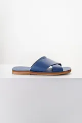 Sandalias bajas de cuero azul con tiras anchas cruzadas sobre el empeine y suela plana color madera.