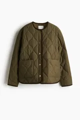 Campera de tejido guateado color verde oliva con ribetes de pana en contraste. Presenta cuello redondo, cierre frontal con botones a presión, bolsillos delanteros de parche y bajo recto con aberturas laterales redondeadas.