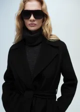 Abrigo tipo batín de lana reciclada en color negro, con diseño oversize, cuello con solapas, cinturón desmontable y bolsillos delanteros.