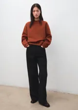 Jersey de punto liso en color marrón terracota, con cuello redondo y diseño de manga larga con puños y bajo de canalé.