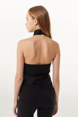 Top negro estilo halter confeccionado en lino, con ajuste cruzado en el cuello y calce al cuerpo.