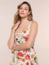 Vestido midi evasé de lino estampado con diseño floral multicolor sobre base beige. Cuenta con escote cuadrado, tirantes anchos y cierre invisible en la espalda.