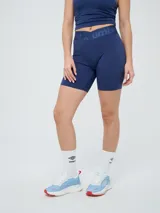 Biker deportiva Umbro para mujer, de color negro, confeccionada con tejido elástico y pretina cruzada con elástico personalizado de la marca.