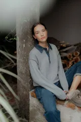 Buzo de punto gris con cuello camisero de denim y cierre frontal parcial con botones metálicos. Presenta mangas largas y un diseño de calce holgado.