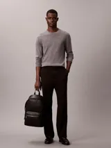 Mochila Calvin Klein negra de poliuretano, con diseño de monograma grabado en relieve, compartimento principal con cierre superior, bolsillo delantero con cremallera, asa de mano superior y tirantes ajustables.
