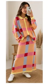 Saco de punto oversize con diseño geométrico de cuadros en tonos naranja, rosa, rojo y celeste. Presenta cuello polo, cierre frontal con botones amarillos y mangas largas con puños en contraste.