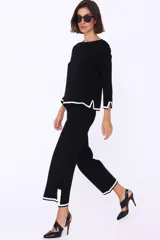 Conjunto de dos piezas de tejido de punto en color blanco con detalles de bordes en negro. Incluye un sweater de corte recto con mangas tres cuartos y un pantalón de corte amplio y largo cropped.