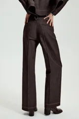 Pantalón de tiro medio en denim oscuro con costuras a contraste. Presenta corte recto, bolsillos delanteros, trabillas en la cintura y cierre frontal con cremallera y ganchos metálicos.