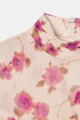 Blusa de cuello subido y manga larga con estampado floral en tonos rosados. Presenta un diseño con volantes en el pecho y a lo largo de las mangas, con cierre posterior mediante botones ocultos.