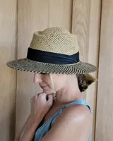 Sombrero de paja color beige con cinta negra y ala ancha.